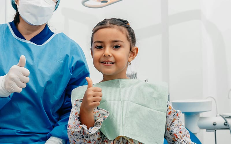 A child and dental hygienist giving thumbs up