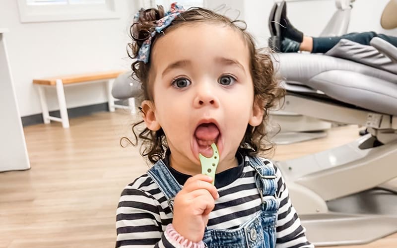 Young girl flossing her teeth in the dentist office