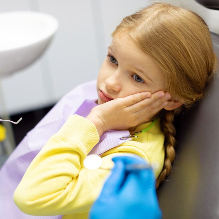 Young girl in dental chair with pain in her mouth