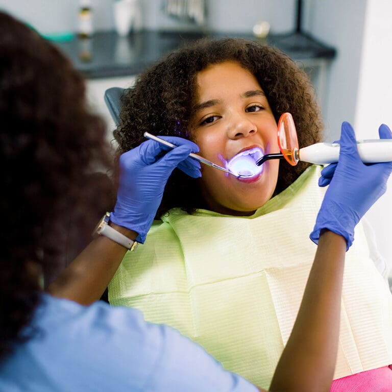Young girl having dental sealants procedure with UV light
