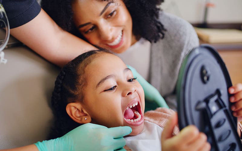 Child and mother in dental chair looking in mirror