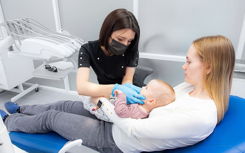 A mother and toddler in a dental chair during routine exam
