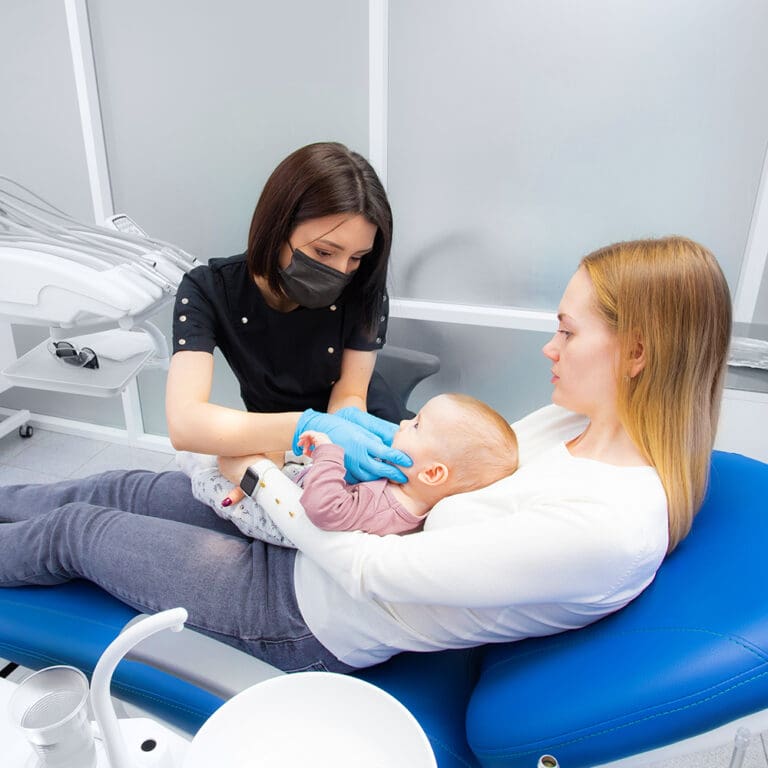 A mother holding her child in a dental chair